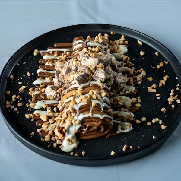 Ranoush dessert: a chocolate crepe drizzled with white and milk chocolate, topped with nuts and candy.
