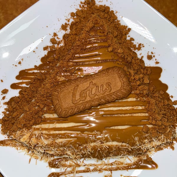 Ranoush dessert with a Lotus Biscoff cookie, crumbled topping, and caramel drizzle on a white plate.