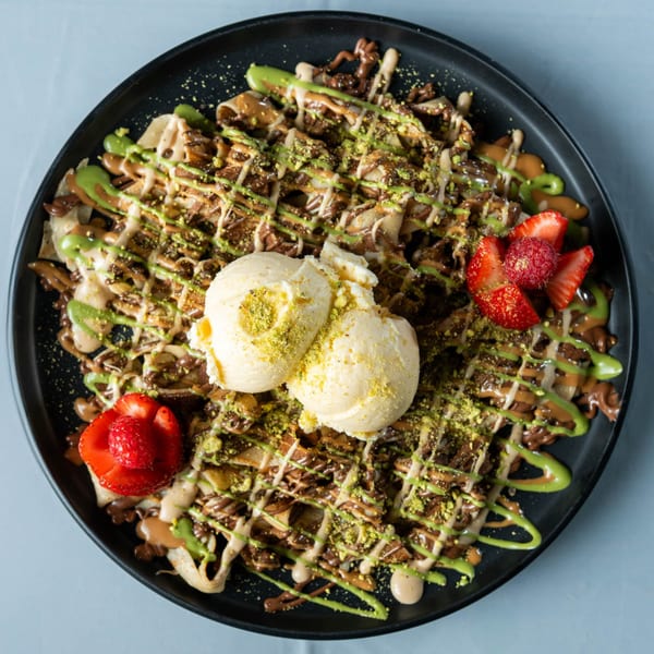 Ranoush dessert crepes drizzled with chocolate and pistachio sauce, topped with ice cream and berries.