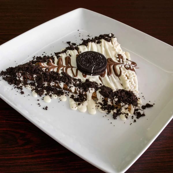 Ranoush dessert crepe drizzled with white and milk chocolate, topped with Oreo crumbles and a cookie.