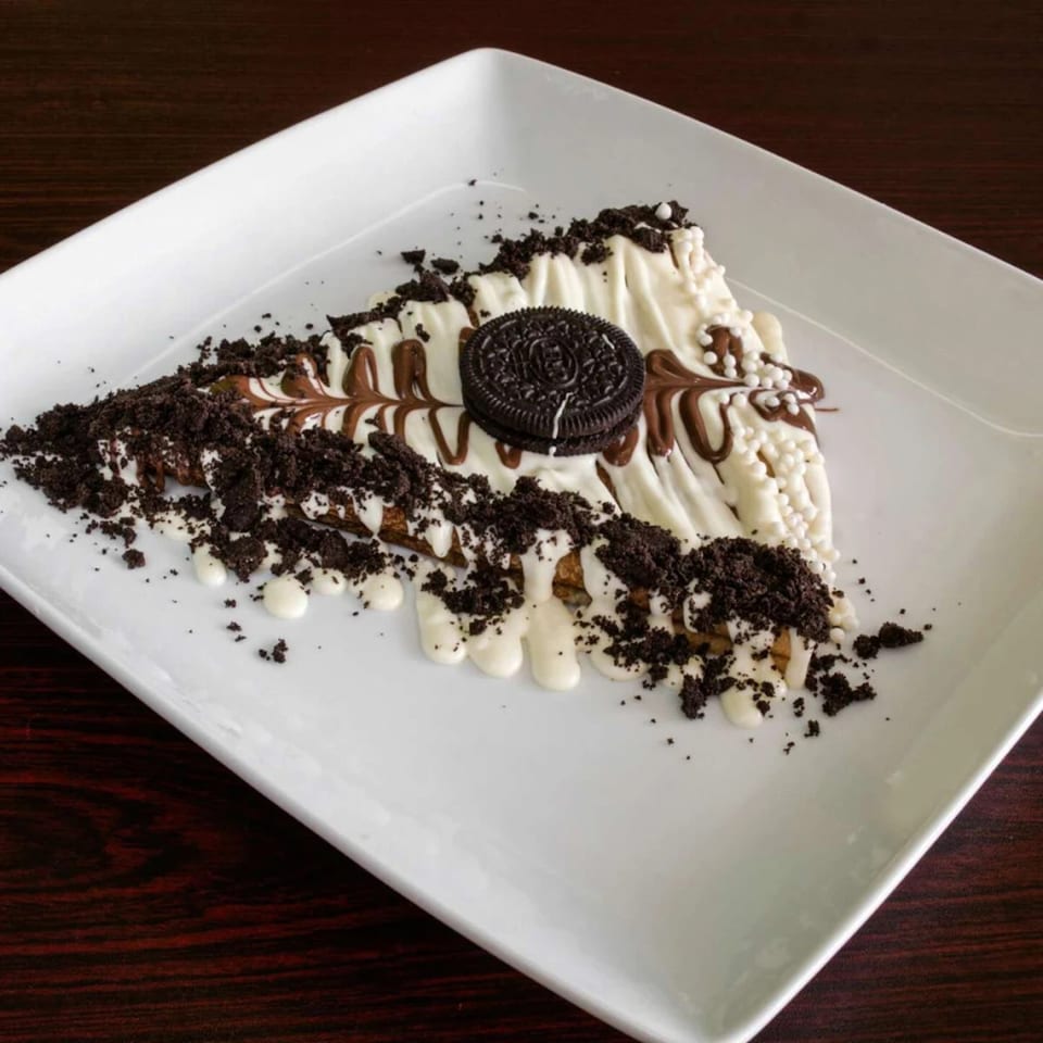 Ranoush dessert crepe drizzled with white and milk chocolate, topped with Oreo crumbles and a cookie.