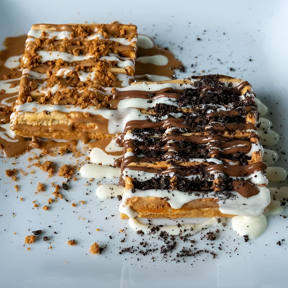 Two Ranoush waffles, one with cookie crumbs and the other with chocolate and cream drizzle.