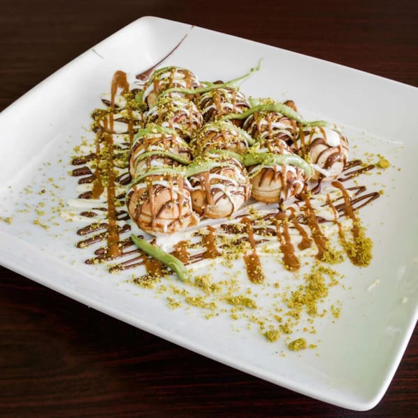 Ranoush dessert: mini pancakes drizzled with chocolate, white sauce, pistachio, and green cream.