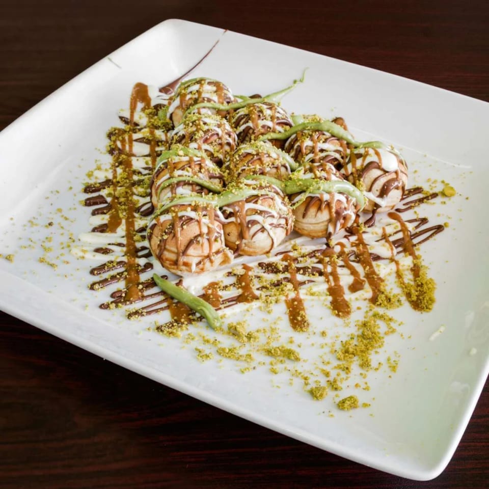 Ranoush dessert: mini pancakes drizzled with chocolate, white sauce, pistachio, and green cream.
